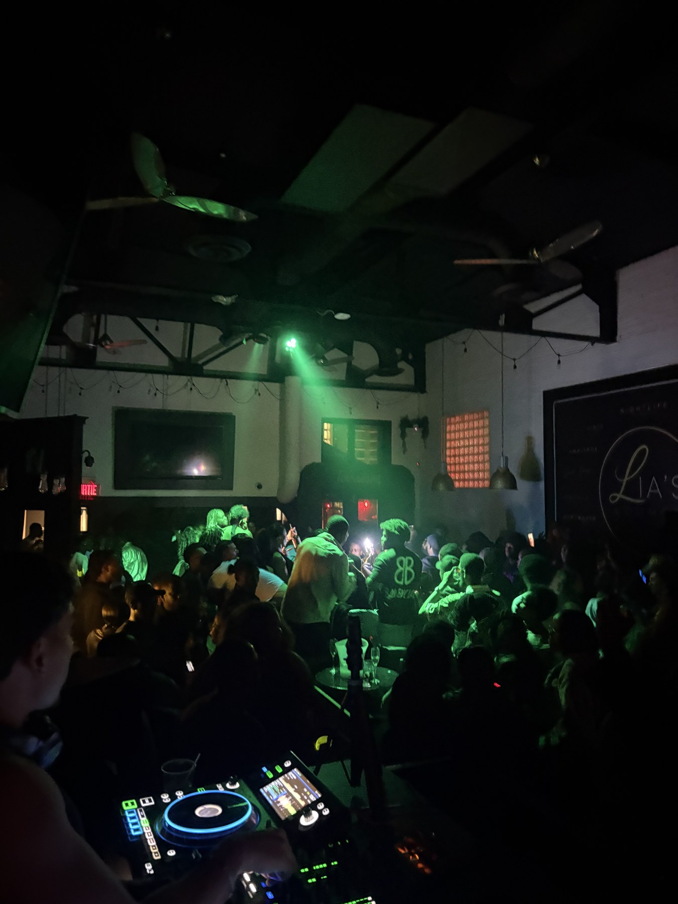 DJ decks overlooking a green-lit crowd